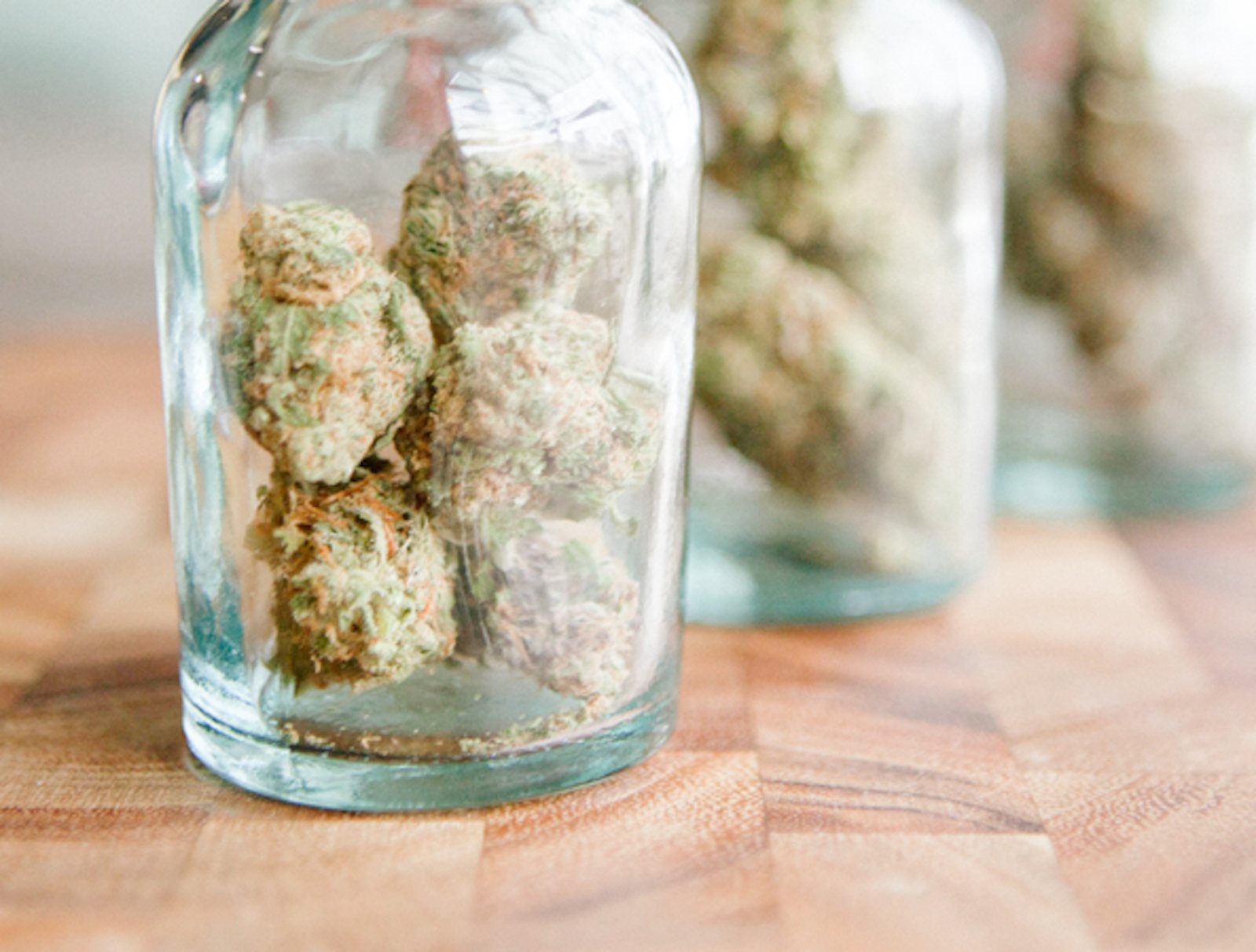 Utopia Gardens: Glass jars of cannabis flower on a wooden counter