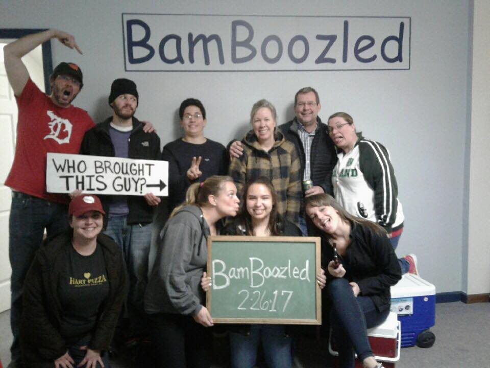 A large, cheerful group poses under the BamBoozled sign holding a chalkboard