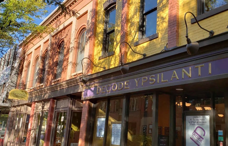 The colorful old brick storefront in sunlight with gold Decode Ypsilanti lettering