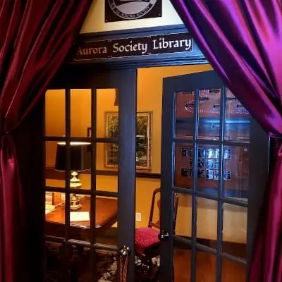 Glass-paned doors framed by purple curtains lead into the Aurora Society Library