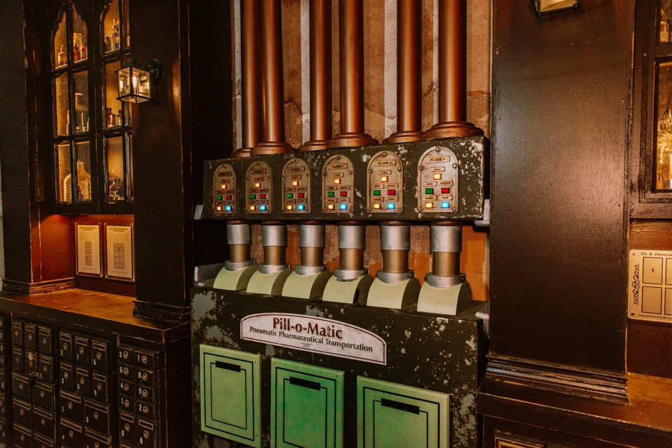 The Pill-o-Matic pneumatic tube machine with colored indicator lights in the pharmacy set