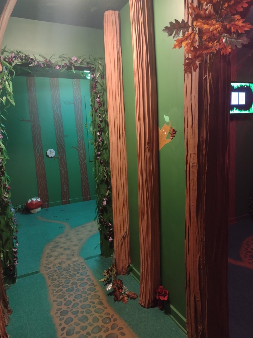Enchanted forest room with painted tree trunks, flower garlands and a stone path painted on the floor