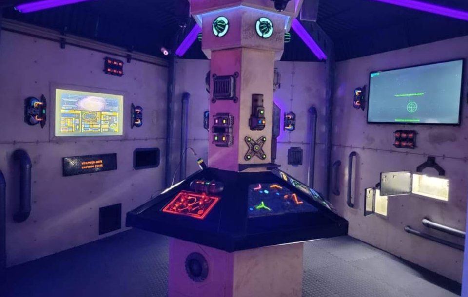 Sci-fi spaceship room with a glowing central control console, screens and wall panels bathed in purple light