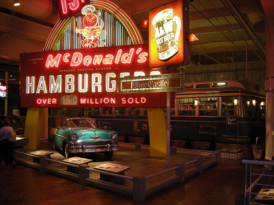 Korai McDonald’s-, A&W- és White Castle-reklámok, egy ötvenes évekbeli Chevrolet és mögöttük a Lamy’s Diner a Driving America kiállításon (2012)