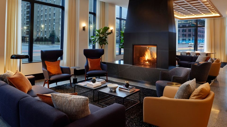 The hotel lobby with a large fireplace, blue armchairs and tall street-facing windows