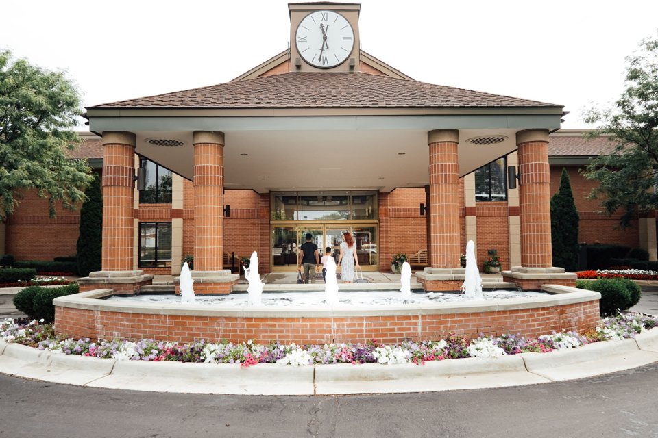The hotel entrance with a clock-tower canopy, brick columns and a fountain