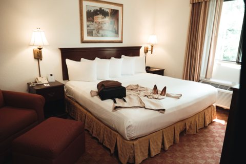 A guest room with a king bed, nightstands and an armchair by the window