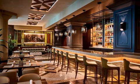 The hotel bar with tall bar stools and lit liquor shelves