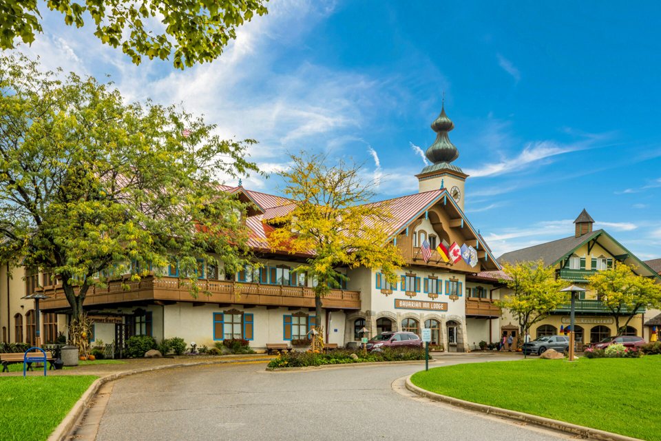 The Bavarian-style lodge building with towers, green lawns and a curving driveway