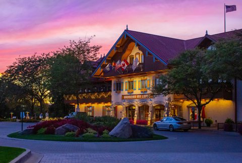 The lodge's lit entrance with a flower bed at sunset