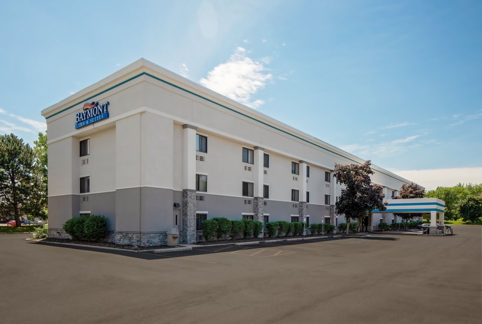 The hotel's light facade and parking lot under a blue sky