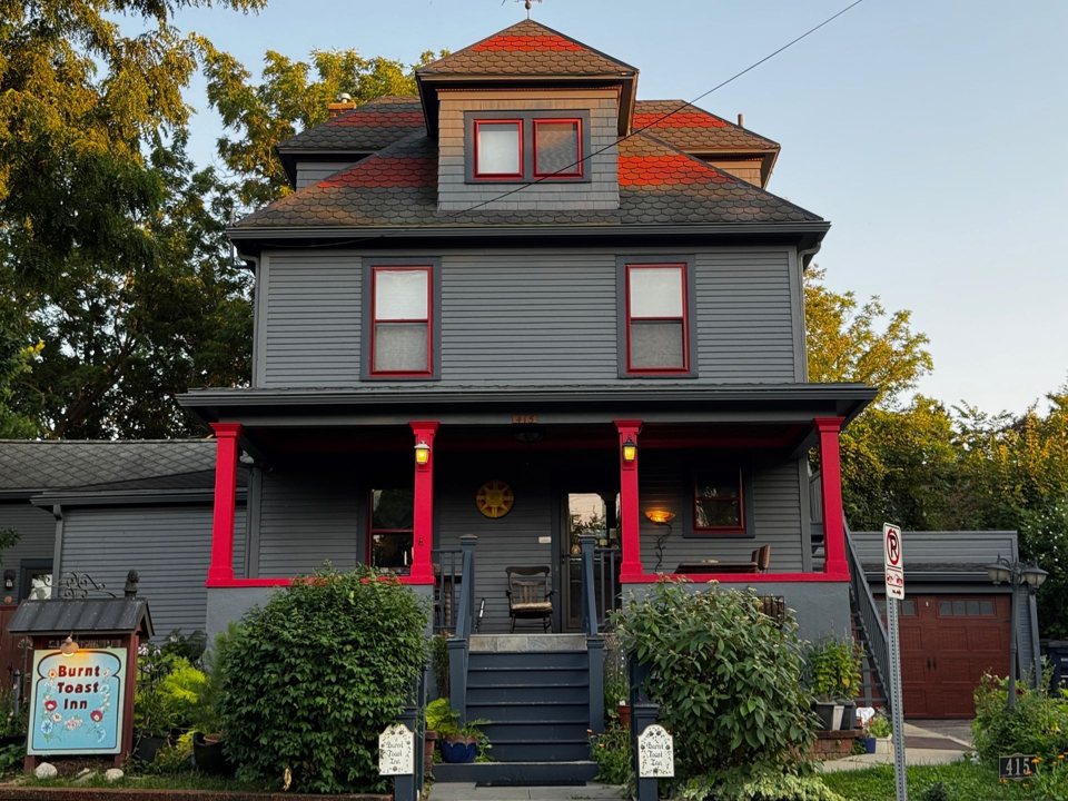 The inn's gray two-storey house with a red-columned porch and the Burnt Toast Inn sign