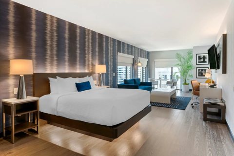 A guest room with a king bed, patterned wallpaper and a seating area