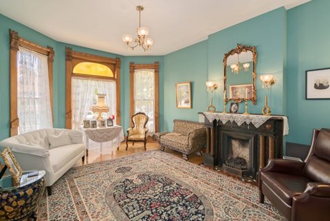 The teal parlor with a fireplace, a chandelier and antique furniture