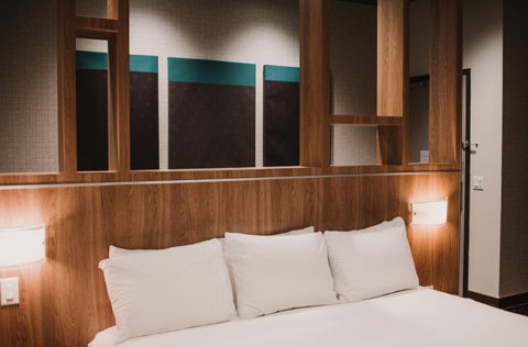 A guest room with a wood-paneled wall and built-in shelves above the bed
