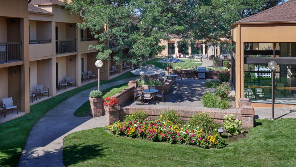 The hotel courtyard with a flower bed, lawn paths and rooms with patios