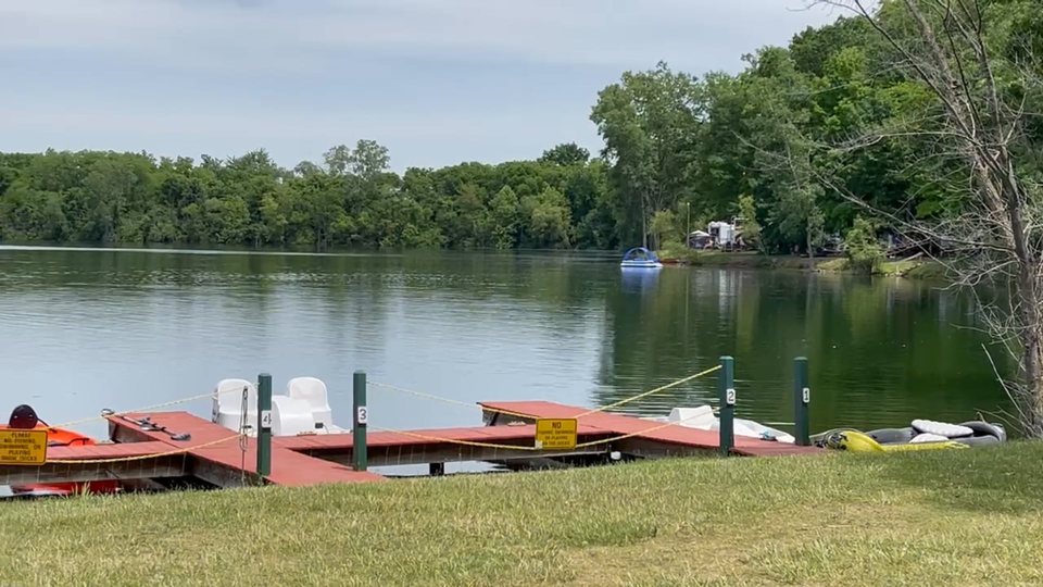 A lake with small boats and a wooded shore at the campground