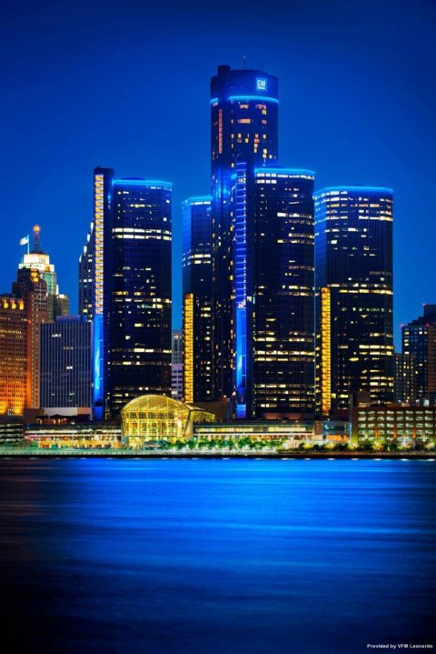 A Renaissance Center tornyai éjszakai kivilágításban a Detroit folyó felől
