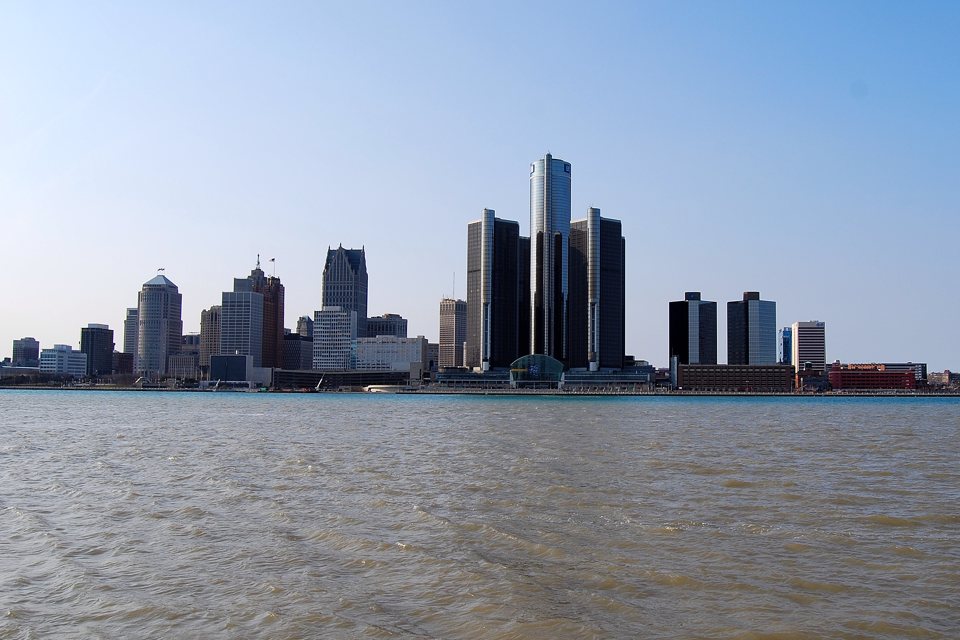 The Renaissance Center towers from across the Detroit River, with the cylindrical hotel tower in the middle