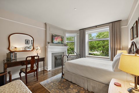 A guest room with a fireplace, a writing desk and a large window