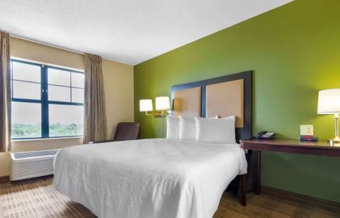A guest room with a bed, green accent wall and window