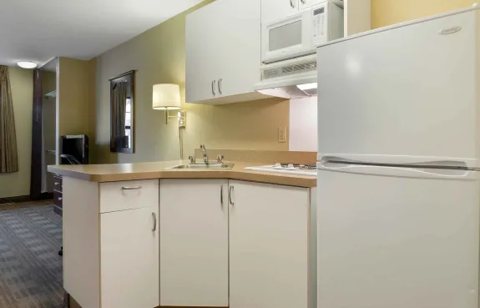 A kitchenette with a refrigerator and white cabinets