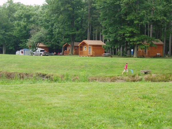 A grassy campground area with cabins in the background
