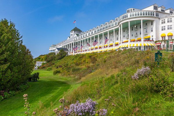 The Grand Hotel's white facade with its long columned porch and flags on top of a green hill
