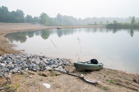The campground lake with rocks and a boat on the shore