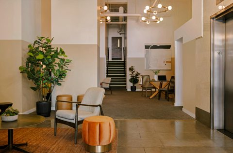 The hotel lobby with armchairs, potted plants and a staircase next to the elevators