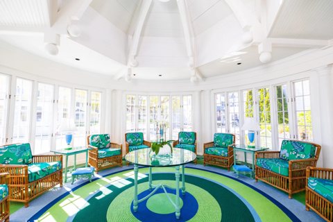 The hotel's round, glass-walled sunroom lounge with green-patterned wicker armchairs