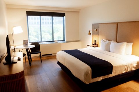 A guest room with a king bed, wood floors and a table by the window
