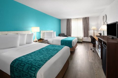 A guest room with two beds and a teal accent wall