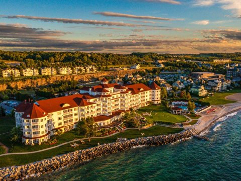 Aerial view of the hotel, its pool and the rocky lakeshore at sunset