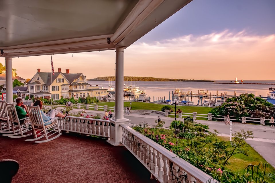 Kilátás az Island House tornácáról hintaszékekkel a Mackinac-szigeti kikötőre naplementekor
