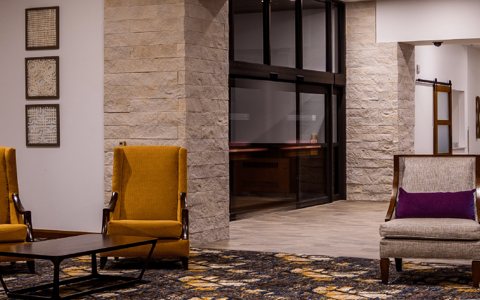 The hotel lobby with a glass-walled fireplace, armchairs and the front desk