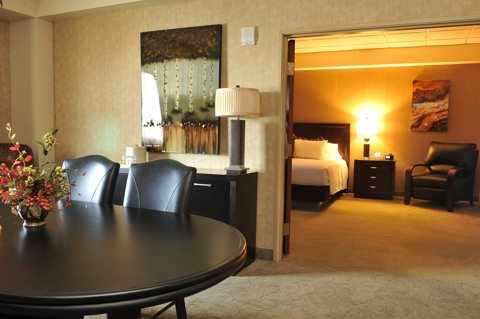 A suite with a dining table and an open door to the bedroom