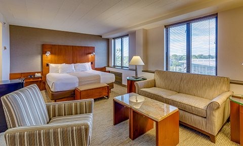 A spacious guest room with a bed and a separate sitting area with a sofa