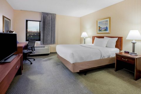 A guest room with a king bed, a desk and a window