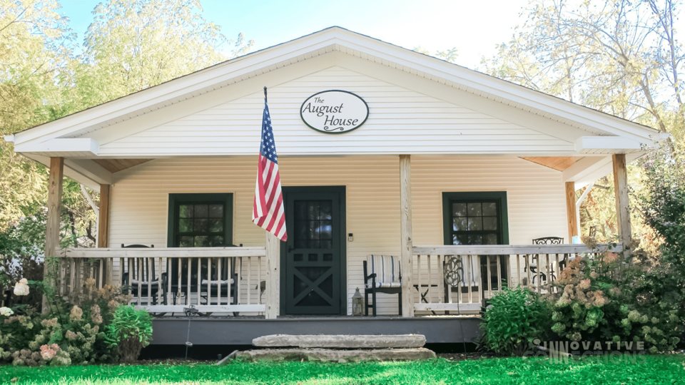 The white guest house with its porch and an American flag