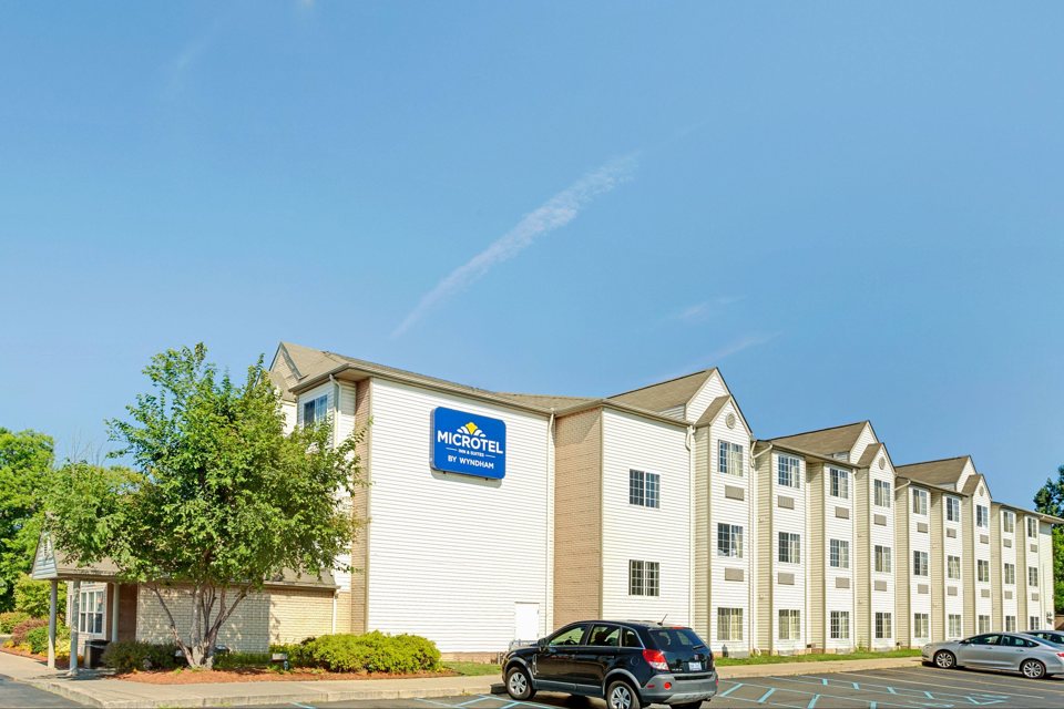 The hotel's light three-storey building under a blue sky
