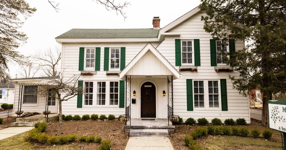 The white guest house with green shutters and the entry walkway
