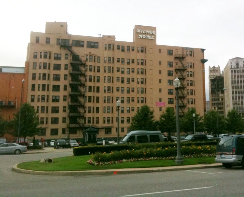The Milner Hotel's beige multi-story facade with its rooftop sign and outdoor fire escapes in August 2012