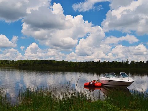 A motorboat on the lake shore beneath a cloudy sky