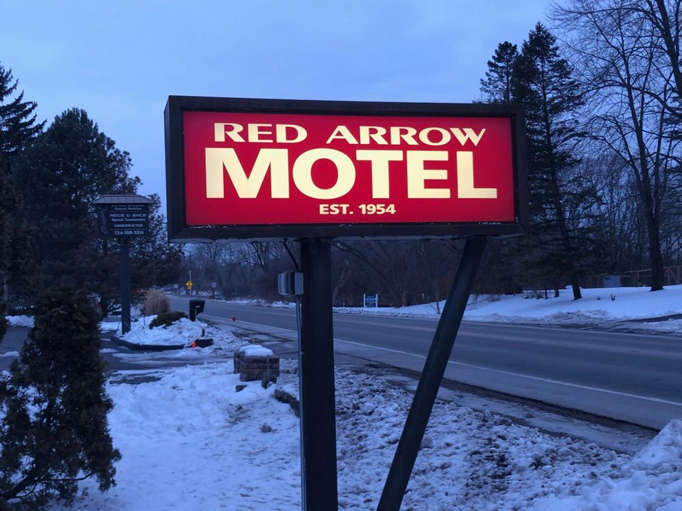 The Red Arrow Motel's lit red roadside sign on a snowy winter evening