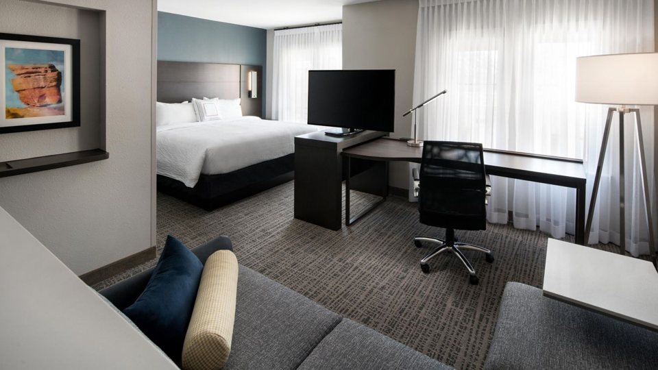 A suite with a queen bed, work desk and sofa at the Residence Inn Dearborn
