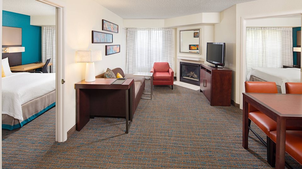 A suite with a sleeping area, dining table and seating corner at the Residence Inn Livonia