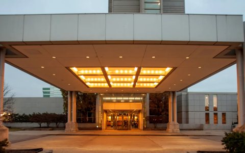 The hotel's lit main entrance under a columned canopy at dusk