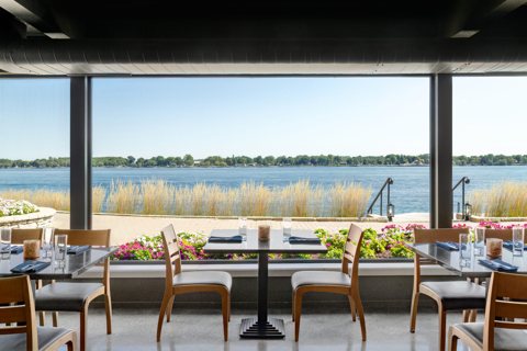 The restaurant's set tables in front of a glass wall overlooking the river