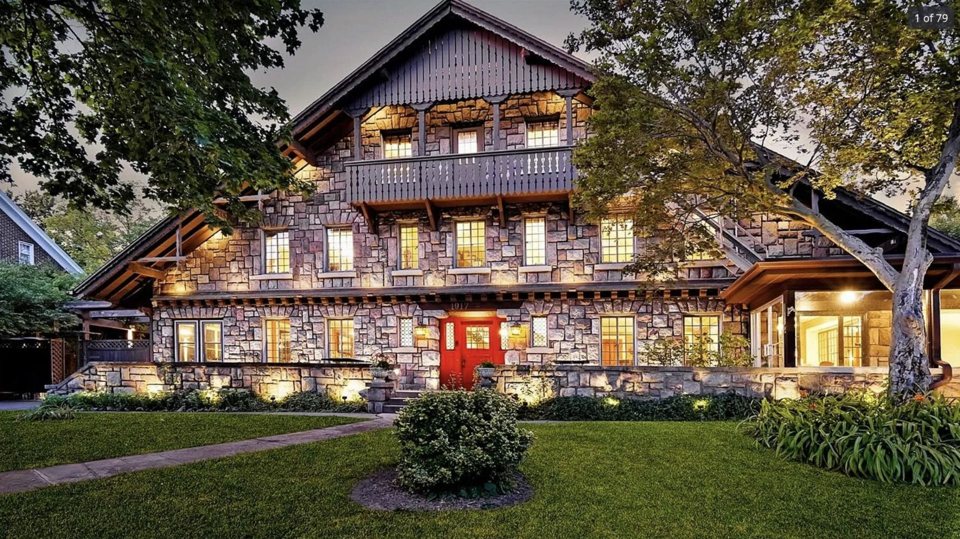 A Stone Chalet kőből és fából épült főháza kivilágítva alkonyatkor, előtte gyepes kerttel